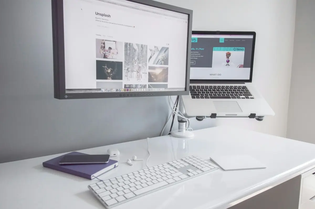 Moderner Arbeitsplatz mit Monitor, Laptop und Tastatur — IT-Infrastruktur sichtbar am Schreibtisch des Mitarbeiters