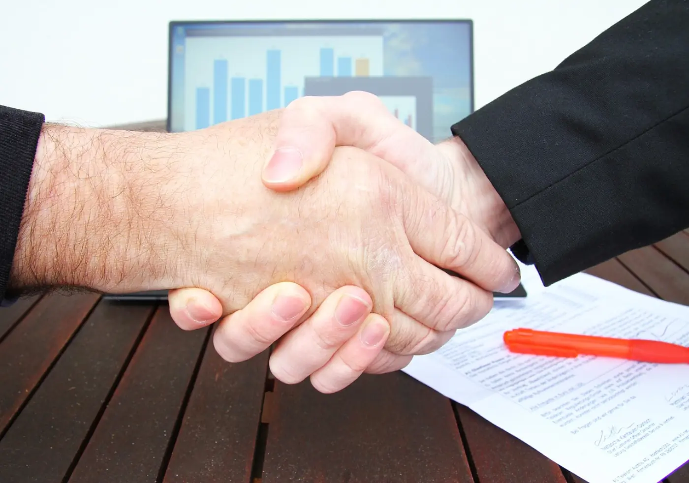 Geschäftsleute schließen Deal per Handschlag — IT-Beschaffung über Einkaufsgemeinschaften und Volumenverhandlung