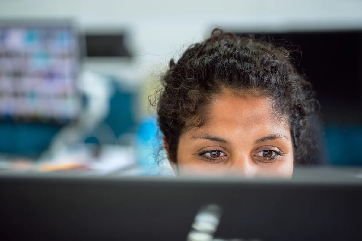 Ergonomie am Dual-Monitor-Arbeitsplatz — Mitarbeiterin im Büro am Bildschirm