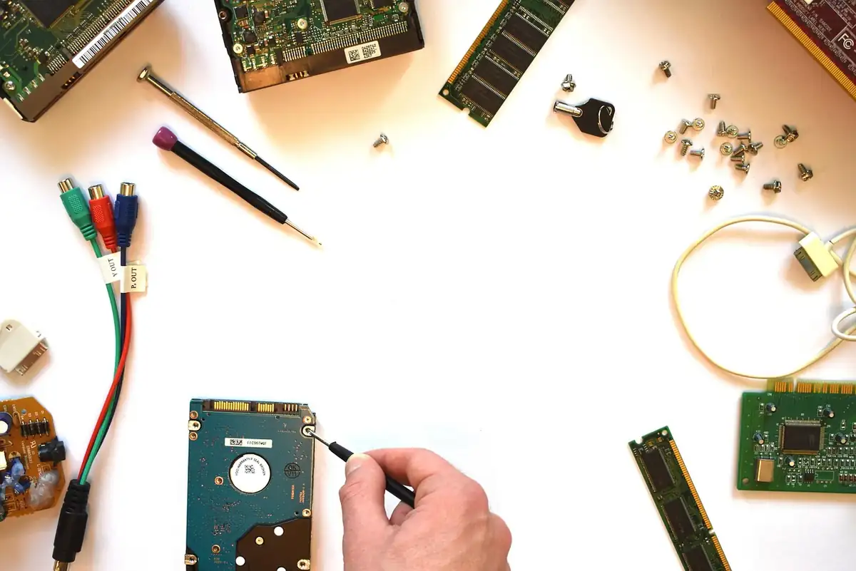 IT-Techniker mit Hardware-Komponenten an einem Arbeitsplatz — Mainboard, Kabel und Werkzeug