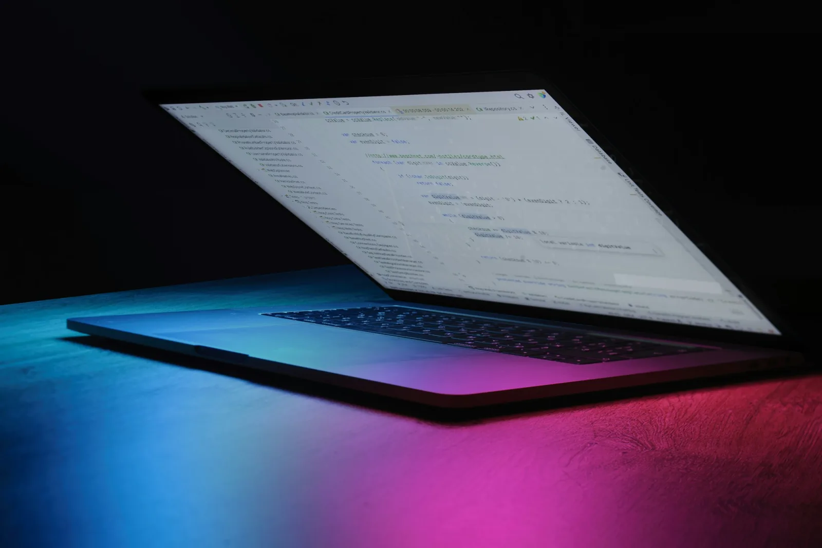 Aufgeklappter Laptop mit Programmcode im Halbdunkel, Sinnbild dafür, die Microsoft 365 Sicherheit zu prüfen