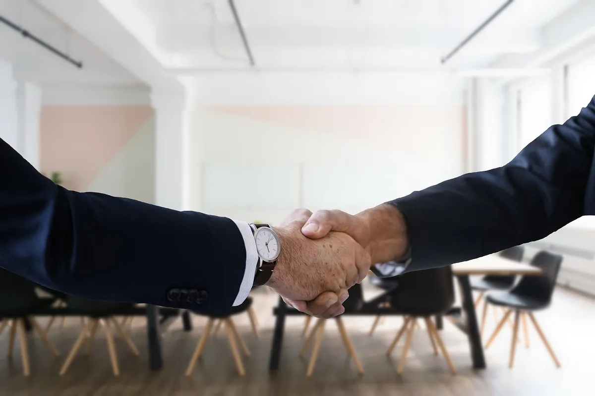 Handschlag zwischen Geschäftsführer und IT-Systemhaus-Berater im modernen Büro — Symbol für eine langfristige Partnerschaft