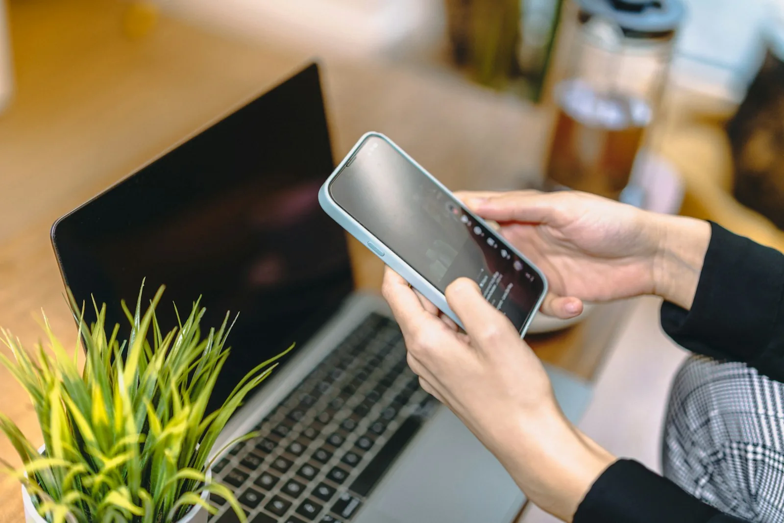 Mitarbeiter hält ein Smartphone mit Anmelde-Bestätigung vor dem Laptop — MFA-Müdigkeit und Push-Bombing-Risiko