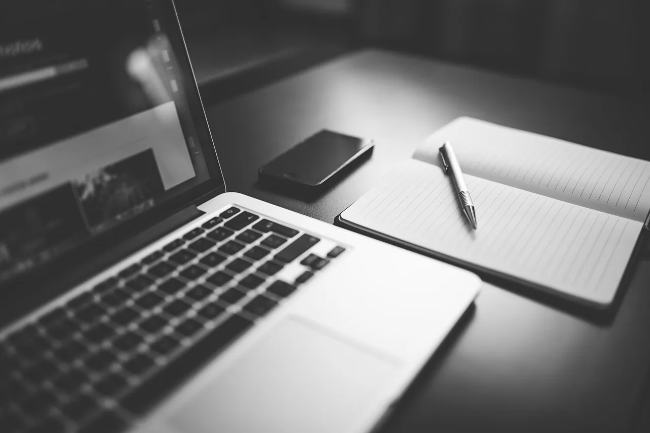 Notebook, Smartphone und Notizbuch auf dem Schreibtisch – Microsoft 365 aufräumen in einer kleinen Beratung