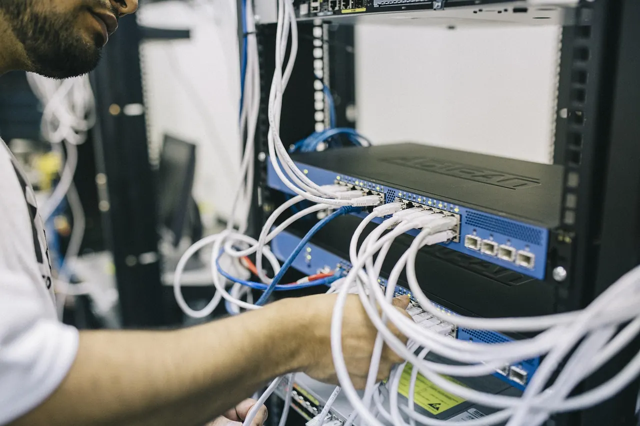 Netzwerk-Techniker verkabelt Glasfaser im Serverraum — Bestandteil einer professionellen Netzwerk-Optimierung