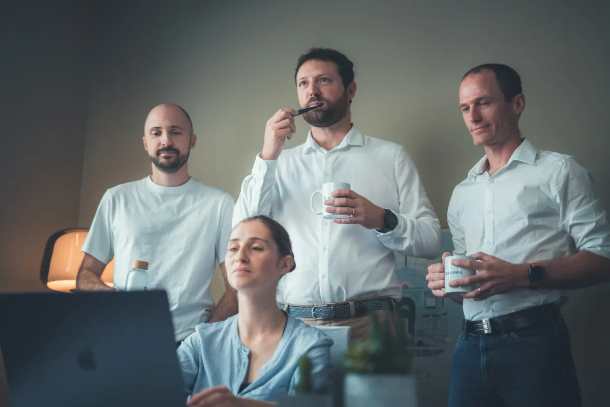 Team am Hot-Desking-Arbeitsplatz mit Laptops, externer Monitor über Dockingstation angeschlossen