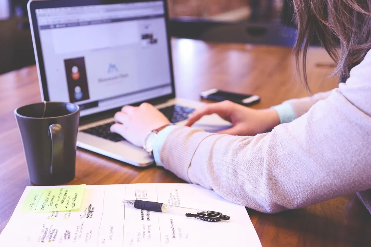 Arbeitsplatz mit Laptop und Smartphone parallel — Wi-Fi-Direct-Risiko, wenn Miracast-Empfang oder Drucker-Pairing unkonfiguriert bleibt